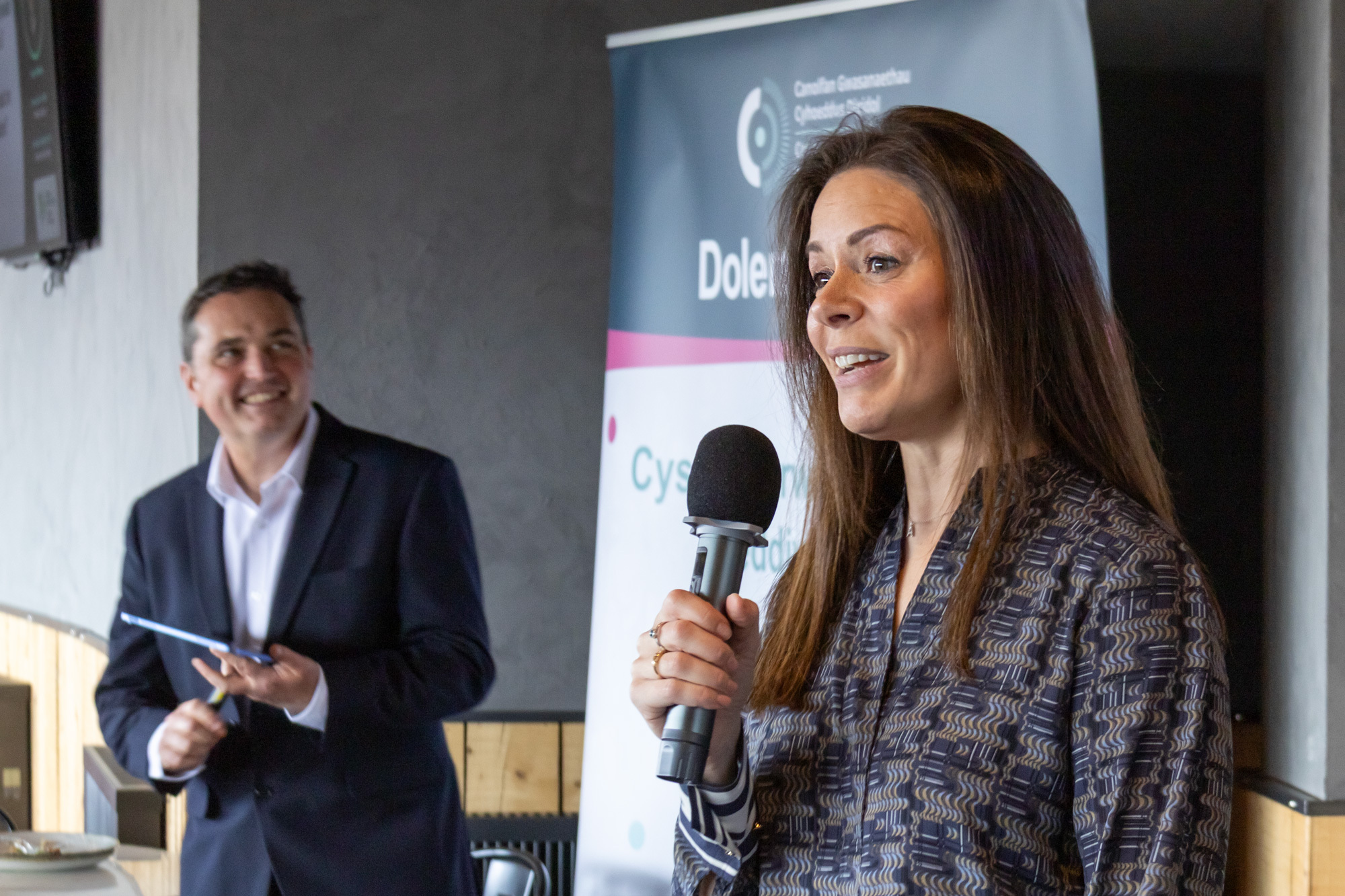 Alwen Williams holding a microphone while she talks at the Dolenni Digidol leadership event in Wrexham.